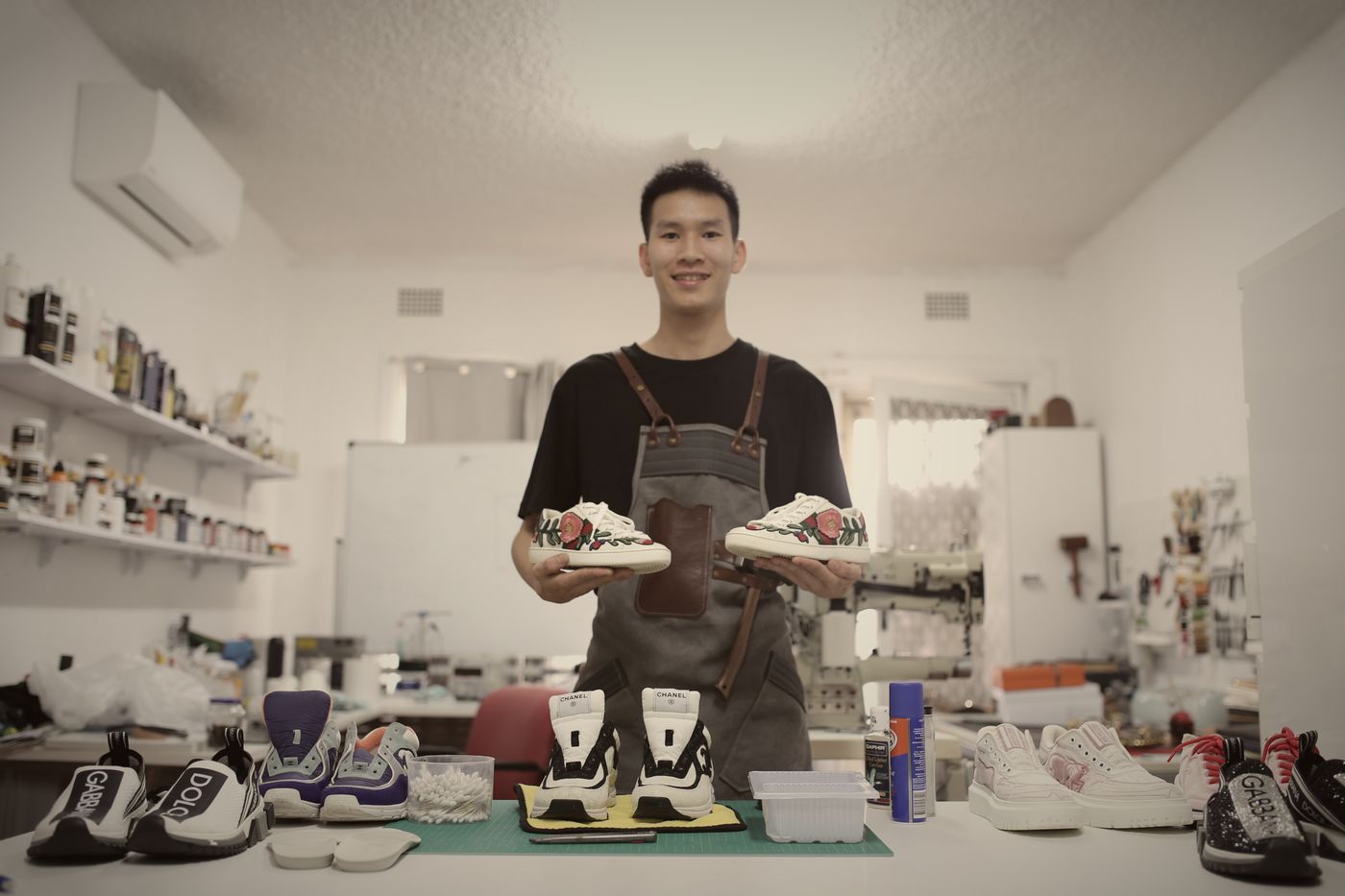 Victor Vu in his Sydney workshop, holding a pair of restored sneakers